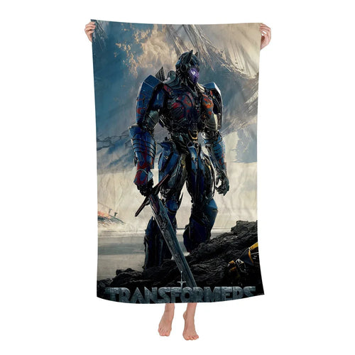 Serviette de bain décorée d’un robot bleu debout avec épée, décor de bataille sombre – Transformers.